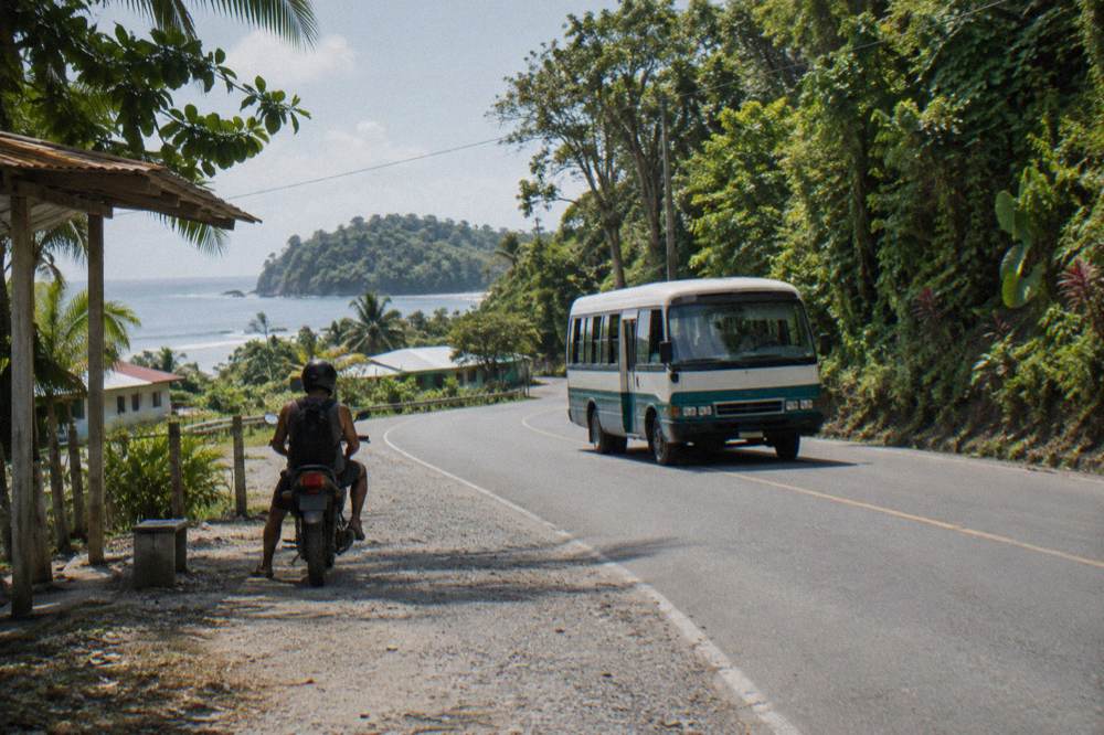 Local bus on the coastal road between Quepos and Manuel Antonio with forested hills behind